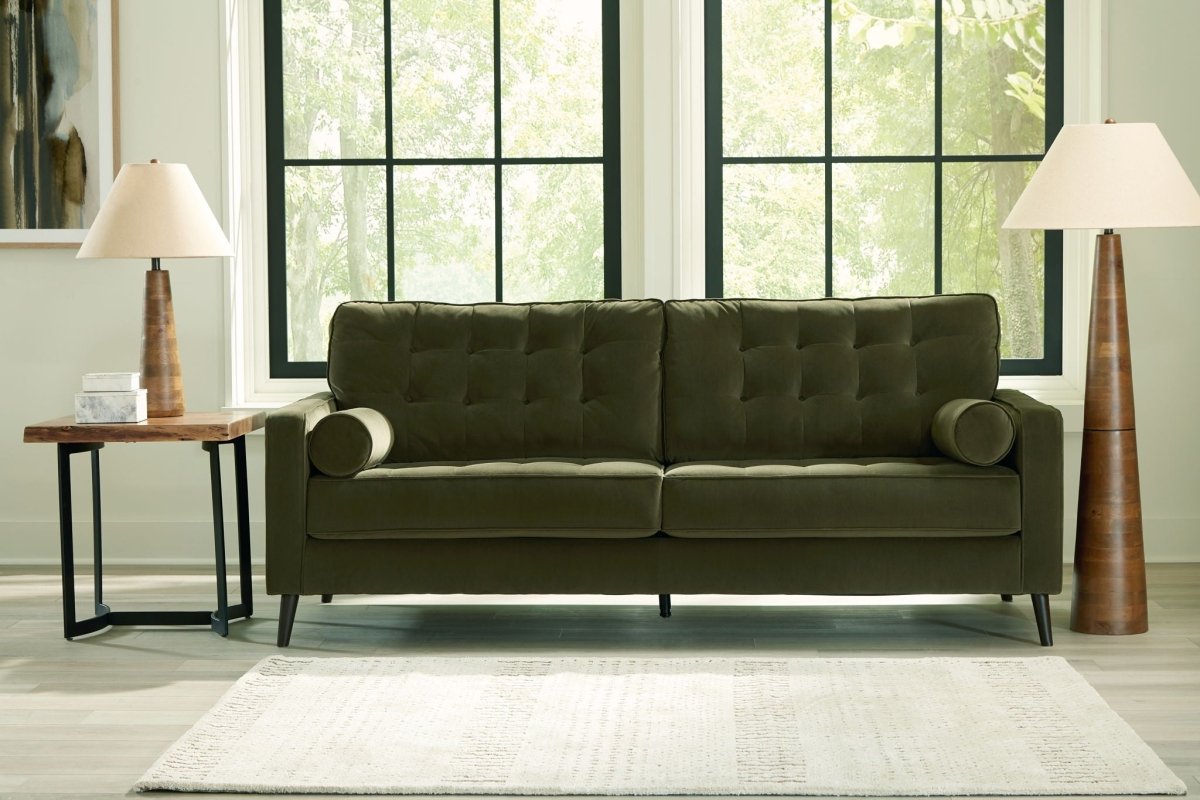 Green sofa in a room with large windows and lamps.