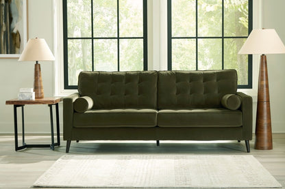 Green sofa in a room with large windows and lamps.